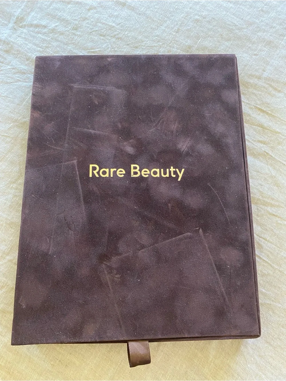 Rare Beauty pressed powder compacts in warm beige and tan tones